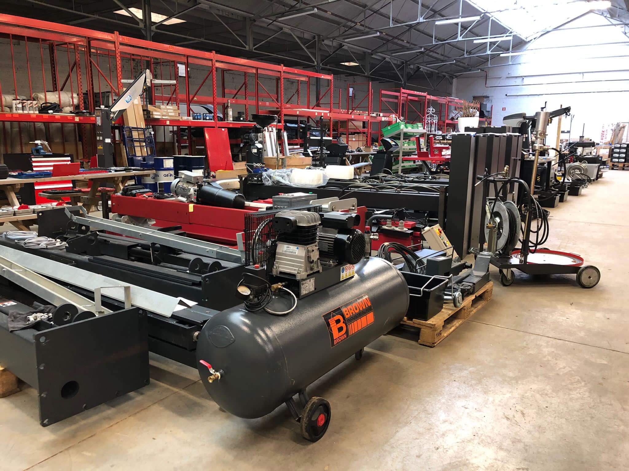 Grote industriële machines, zoals heftrucks en productielijnen, opgeslagen in een loods voor verkoop.