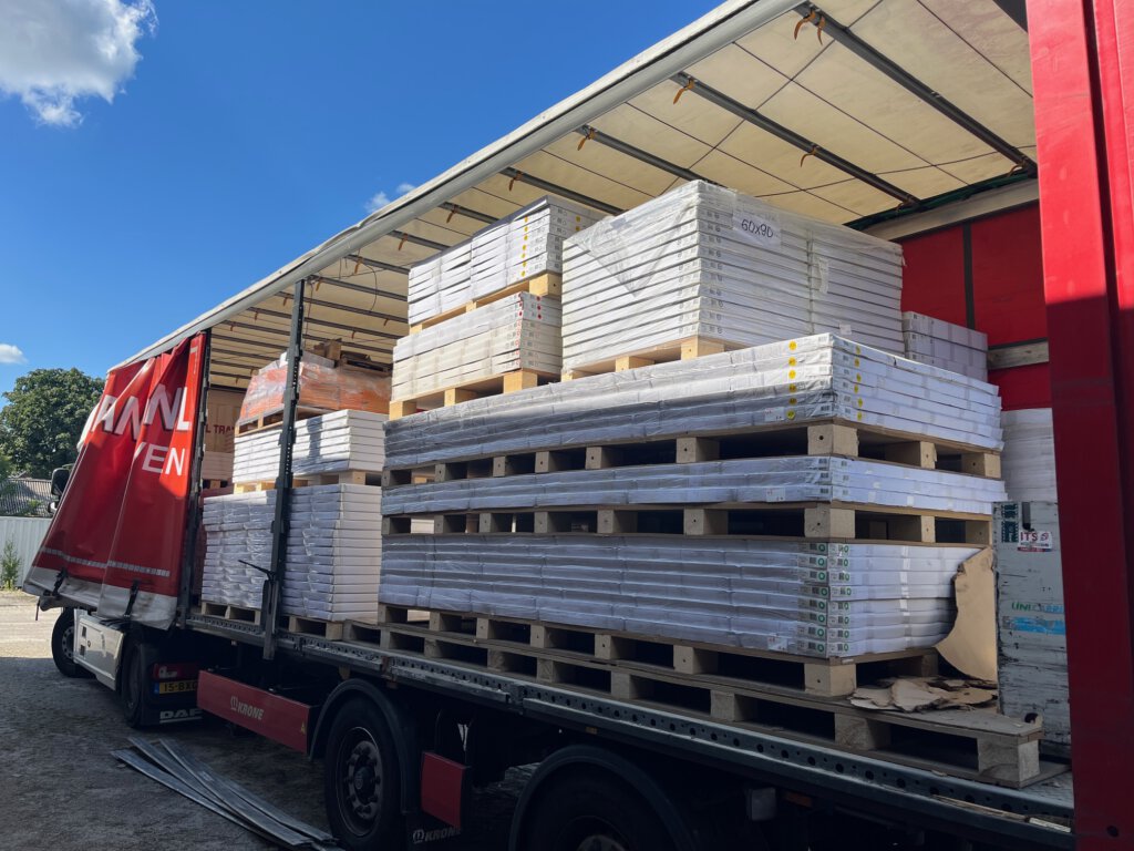 Goederen van SAM International geladen in vrachtwagens voor transport en online veiling
