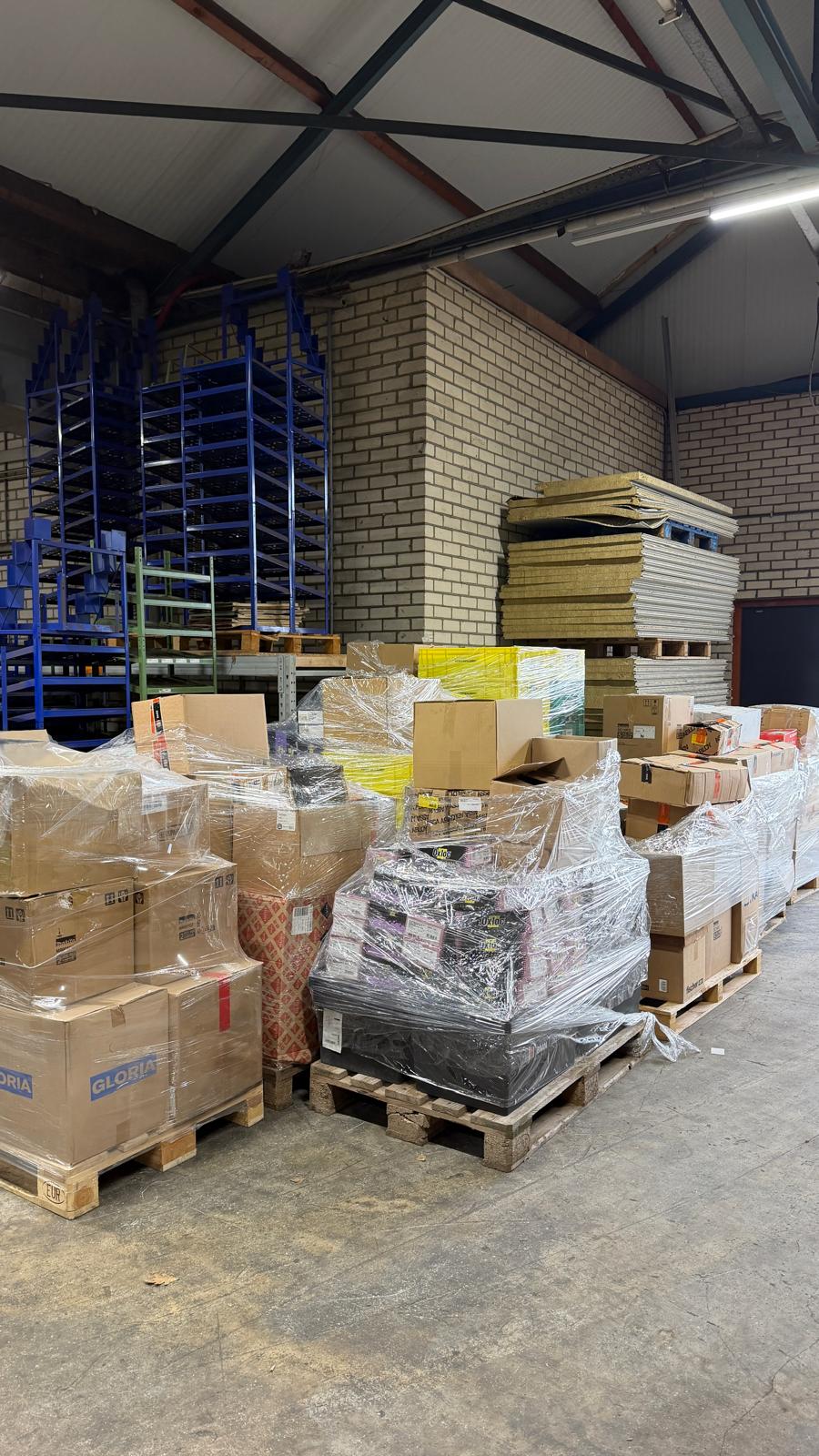 Bouwmaterialen opgeslagen op pallets en in bakken in een bedrijfshal