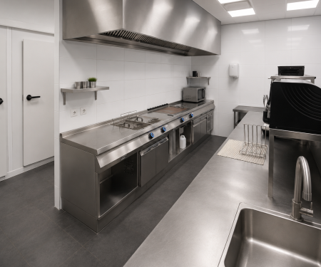 Professionele horeca keuken met bakwand, afzuigkap en RVS kookapparatuur.